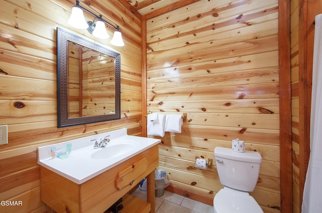 bathroom with tile patterned flooring, vanity, wooden walls, and toilet