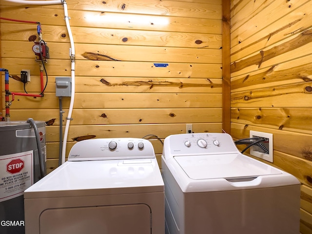 laundry room with electric water heater, wooden walls, and washer and clothes dryer