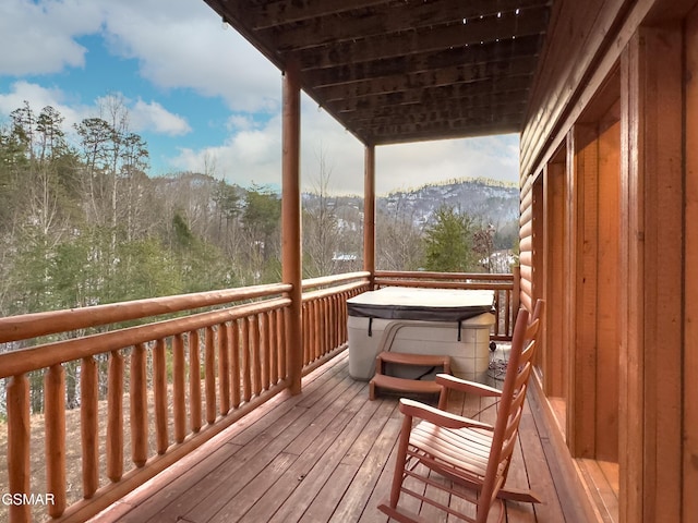 wooden terrace with a hot tub and a mountain view