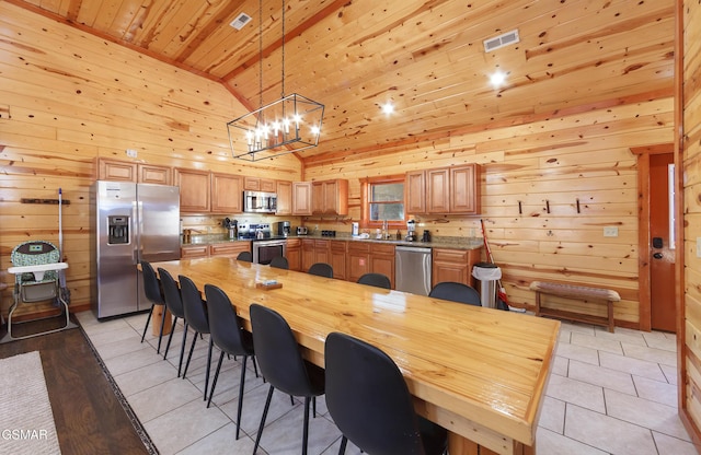 tiled dining space featuring sink, wood walls, wood ceiling, an inviting chandelier, and high vaulted ceiling