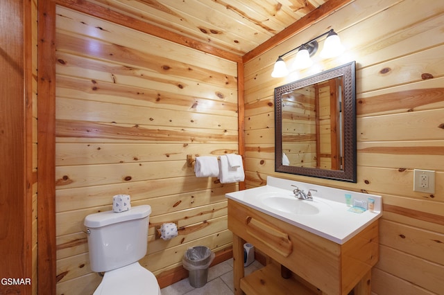 bathroom featuring tile patterned flooring, sink, wooden walls, and toilet