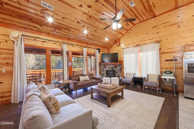 living room with a stone fireplace, high vaulted ceiling, wood walls, ceiling fan, and wooden ceiling