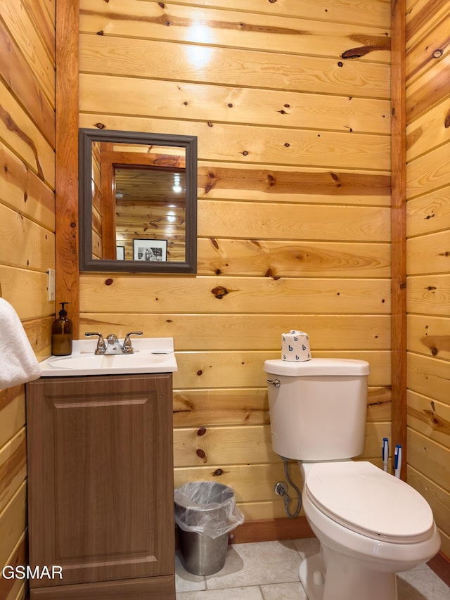 bathroom featuring vanity, wooden walls, and toilet