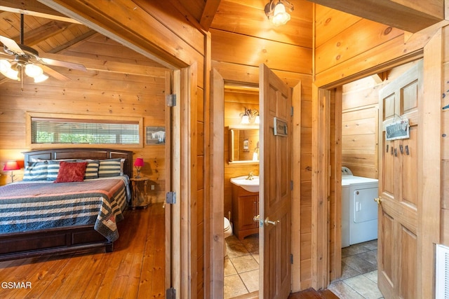 bedroom featuring wood ceiling, ceiling fan, connected bathroom, washer / clothes dryer, and beamed ceiling