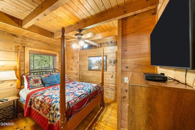 bedroom featuring ceiling fan, beamed ceiling, wooden walls, and hardwood / wood-style floors