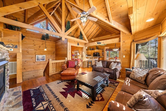 living room with a fireplace, beamed ceiling, wood walls, and hardwood / wood-style floors