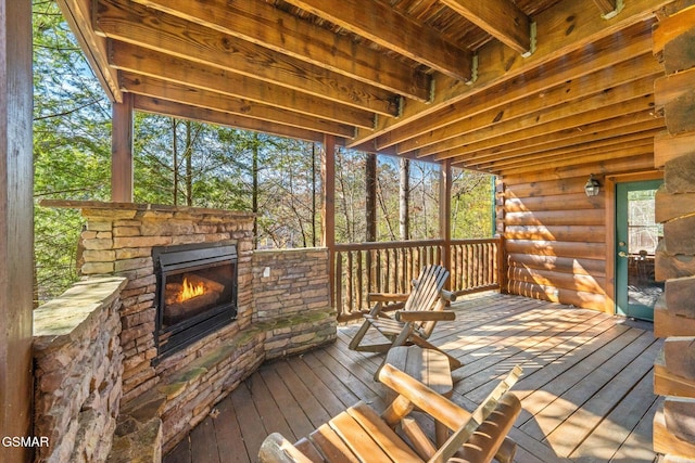 wooden terrace with an outdoor stone fireplace