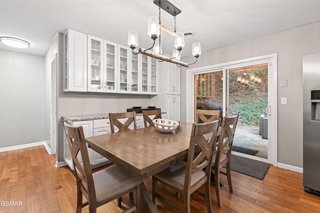 dining area featuring light wood-type flooring and an inviting chandelier