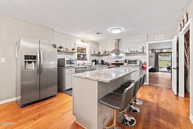 kitchen with backsplash, sink, a breakfast bar area, wall chimney exhaust hood, and stainless steel appliances