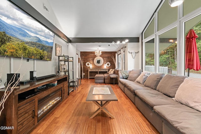 living room featuring hardwood / wood-style flooring, plenty of natural light, lofted ceiling, and an inviting chandelier