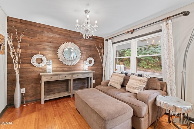 living room with light hardwood / wood-style floors, wooden walls, and a chandelier