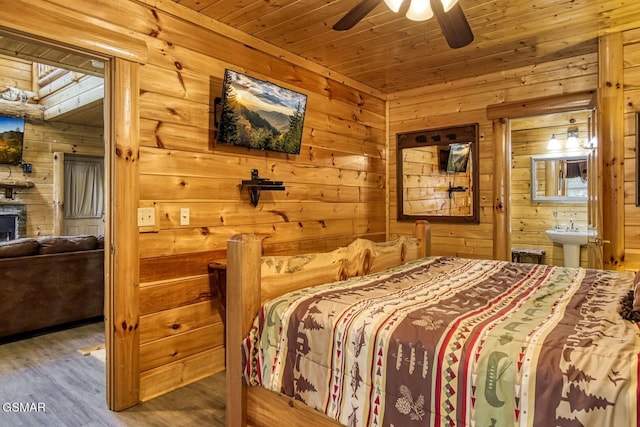 bedroom featuring wooden walls, wood finished floors, connected bathroom, wood ceiling, and ceiling fan