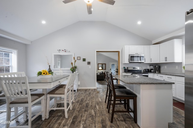 kitchen with vaulted ceiling, stainless steel appliances, dark wood-style flooring, and white cabinetry