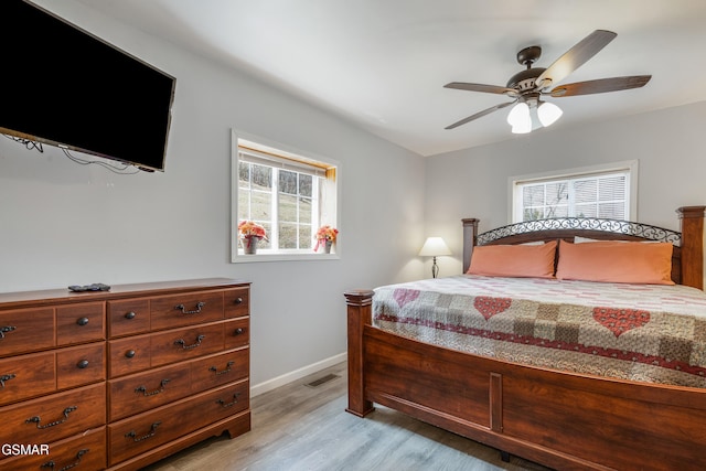 bedroom with light wood finished floors, a ceiling fan, visible vents, and baseboards