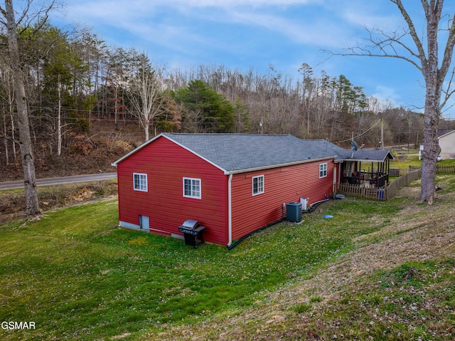 view of home's exterior with a shingled roof, cooling unit, and a yard