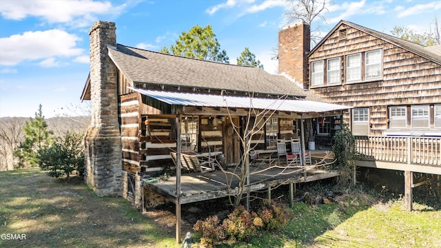 back of property featuring a wooden deck, a chimney, and roof with shingles