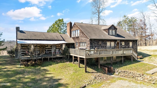 rear view of property featuring a chimney, a lawn, and a wooden deck