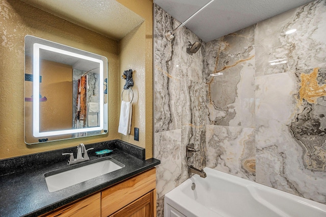 bathroom featuring tiled shower / bath, vanity, and a textured ceiling