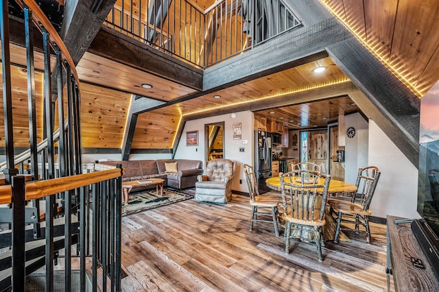 dining room featuring wood ceiling, hardwood / wood-style flooring, and a high ceiling