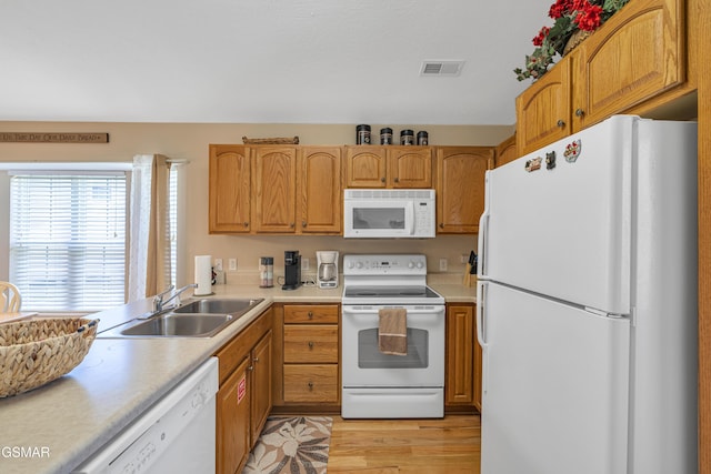 kitchen with white appliances, a sink, light countertops, and light wood finished floors