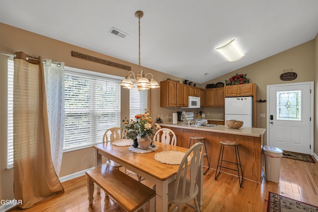 dining space featuring lofted ceiling, light wood-style flooring, a chandelier, healthy amount of natural light, and baseboards
