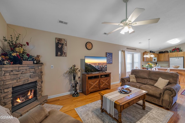 living area with light wood-type flooring, vaulted ceiling, a ceiling fan, a chandelier, and baseboards