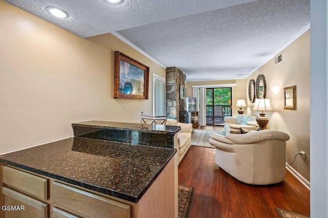 living room featuring dark wood-type flooring, a textured ceiling, and crown molding