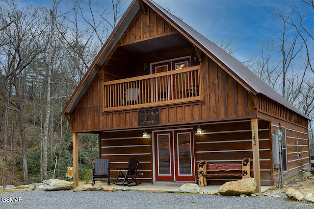 view of front of property with board and batten siding, a balcony, and metal roof