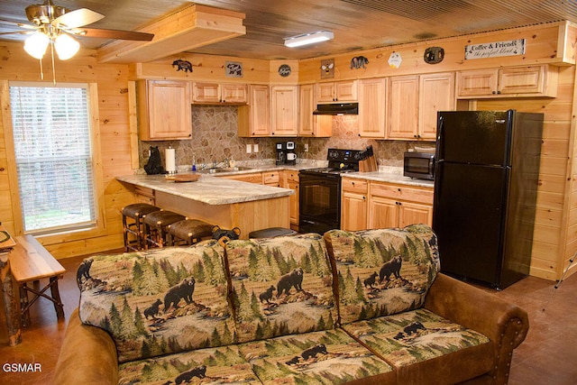kitchen featuring black appliances, under cabinet range hood, light brown cabinetry, and plenty of natural light