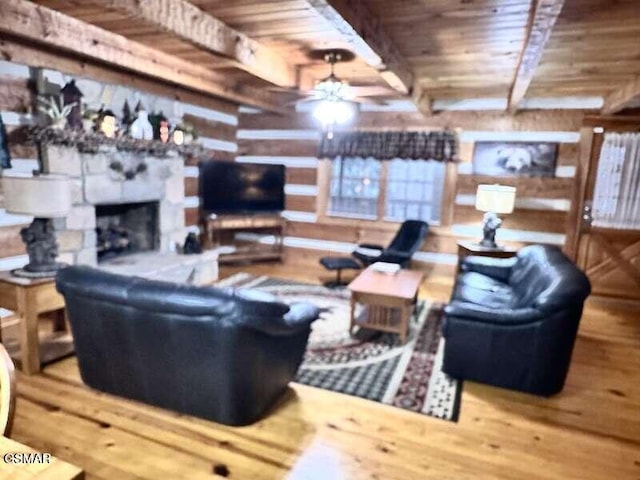 living room with ceiling fan, wooden ceiling, beamed ceiling, and a fireplace