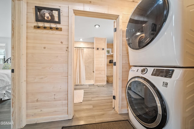 clothes washing area featuring stacked washer and dryer, wood finished floors, recessed lighting, and laundry area