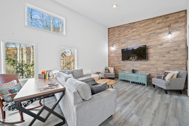 living room featuring wood walls, wood finished floors, and a towering ceiling