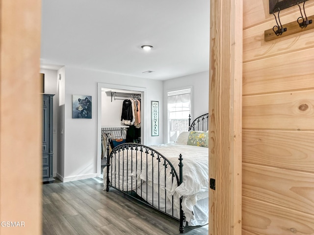 bedroom with baseboards, wood finished floors, and a closet