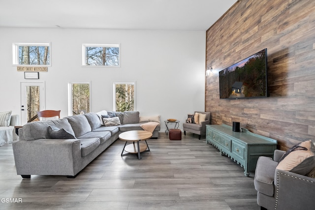 living room featuring a high ceiling, wood finished floors, and wooden walls
