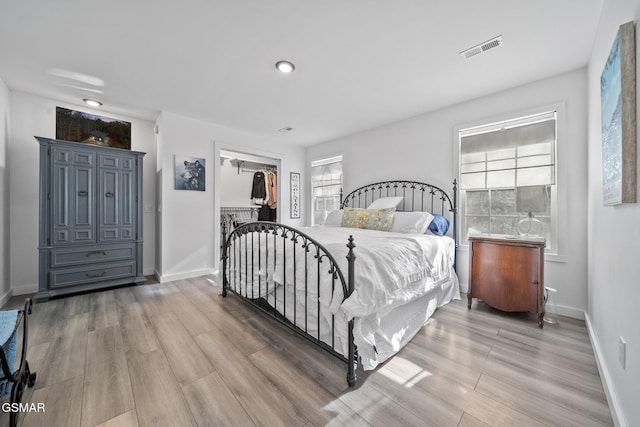 bedroom featuring baseboards, light wood-style floors, visible vents, and a closet