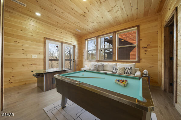 recreation room featuring visible vents, wooden walls, wood ceiling, and wood finished floors