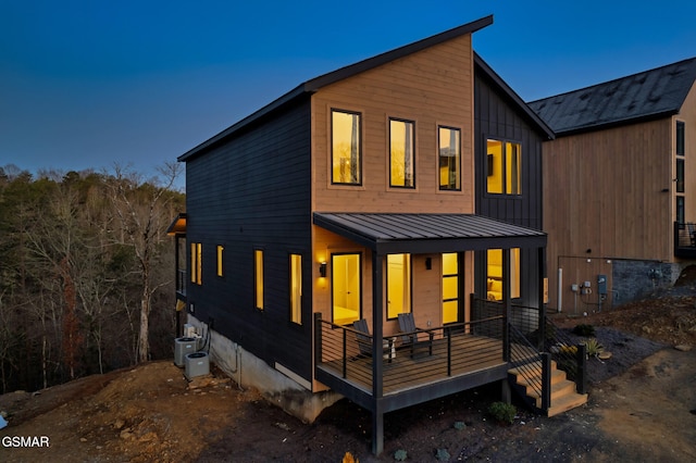 back of property with a standing seam roof, cooling unit, a porch, and metal roof