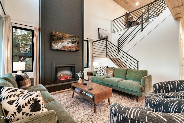 living room with a fireplace, high vaulted ceiling, stairs, wooden ceiling, and wood finished floors