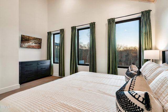 bedroom featuring baseboards, wood finished floors, and vaulted ceiling