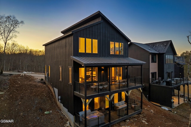 rear view of property with board and batten siding, metal roof, and a standing seam roof