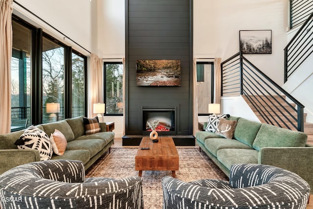 living area with a high ceiling, wood finished floors, stairway, and a fireplace