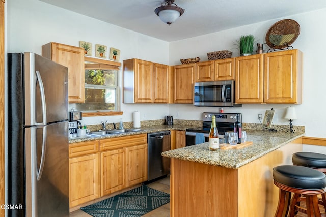 kitchen featuring kitchen peninsula, appliances with stainless steel finishes, light stone countertops, sink, and light tile patterned floors