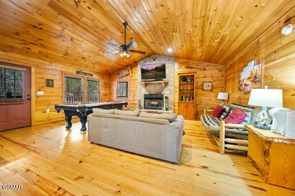 living room with wood walls, lofted ceiling, light hardwood / wood-style floors, and wooden ceiling