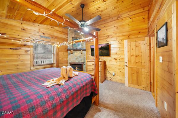 bedroom featuring carpet flooring, wooden ceiling, a fireplace, and wood walls