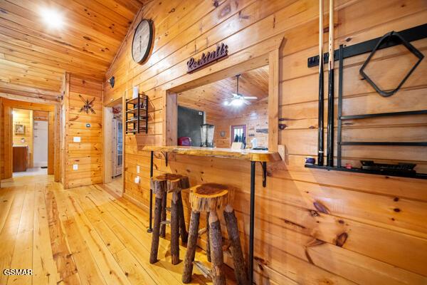 bar featuring light hardwood / wood-style flooring, wood ceiling, vaulted ceiling, and wood walls