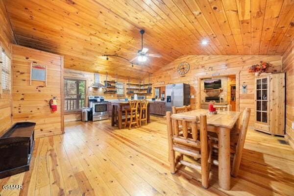 dining room featuring lofted ceiling, wood walls, light hardwood / wood-style flooring, wooden ceiling, and ceiling fan