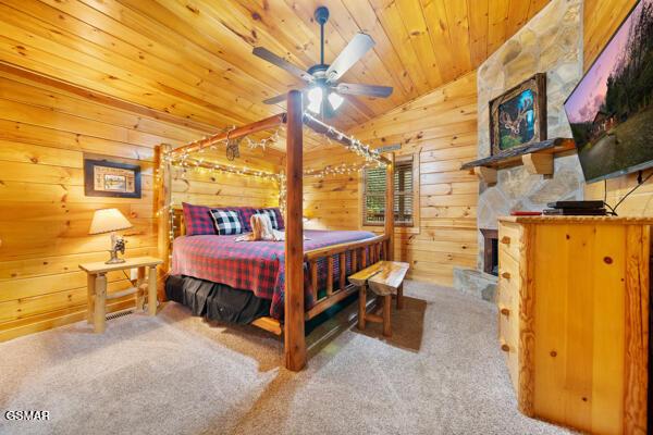 bedroom featuring lofted ceiling, wooden walls, wooden ceiling, and carpet flooring