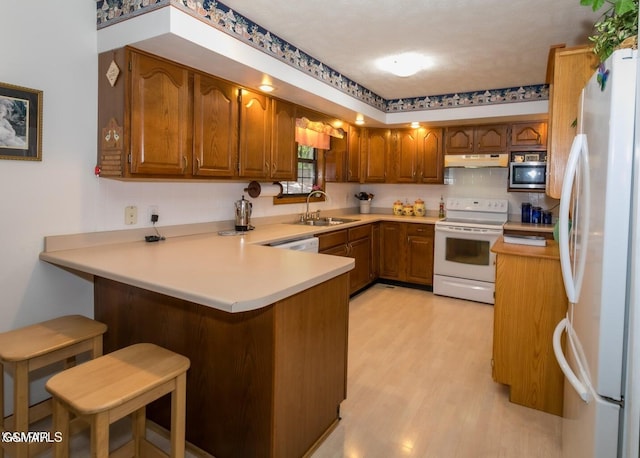 3188 Wears Dr, Sevierville, TN 37862 - kitchen featuring brown cabinets, a sink, white appliances, a peninsula, and under cabinet range hood