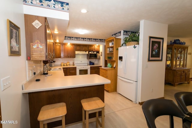 3188 Wears Dr, Sevierville, TN 37862 - kitchen featuring a sink, light countertops, a peninsula, under cabinet range hood, and white appliances
