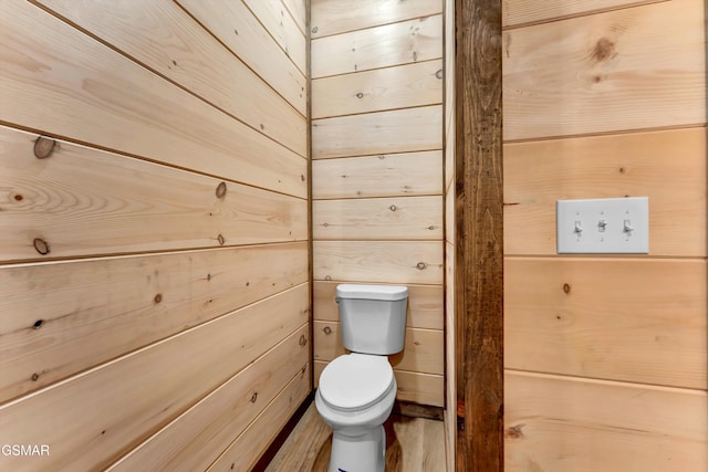 bathroom with toilet and wood walls